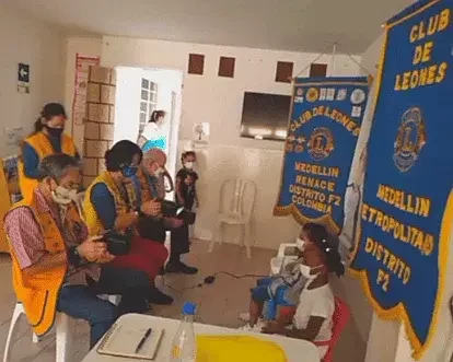 Miembros del club realizando tamizaje visual a niños durante brigada comunitaria